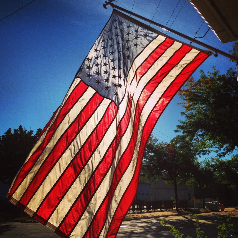 sun shining through the flag hanging proudly from my porch